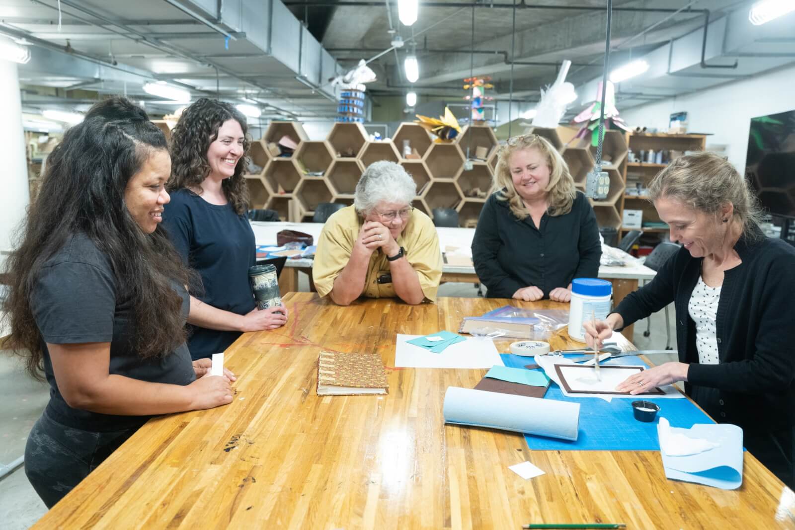Women watch art instructor paint during an adult education class.
